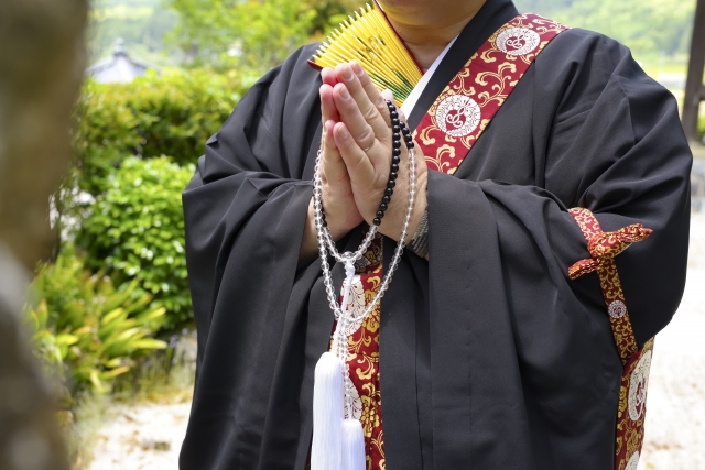 お墓の前でお性根抜き（閉眼）供養をする僧侶